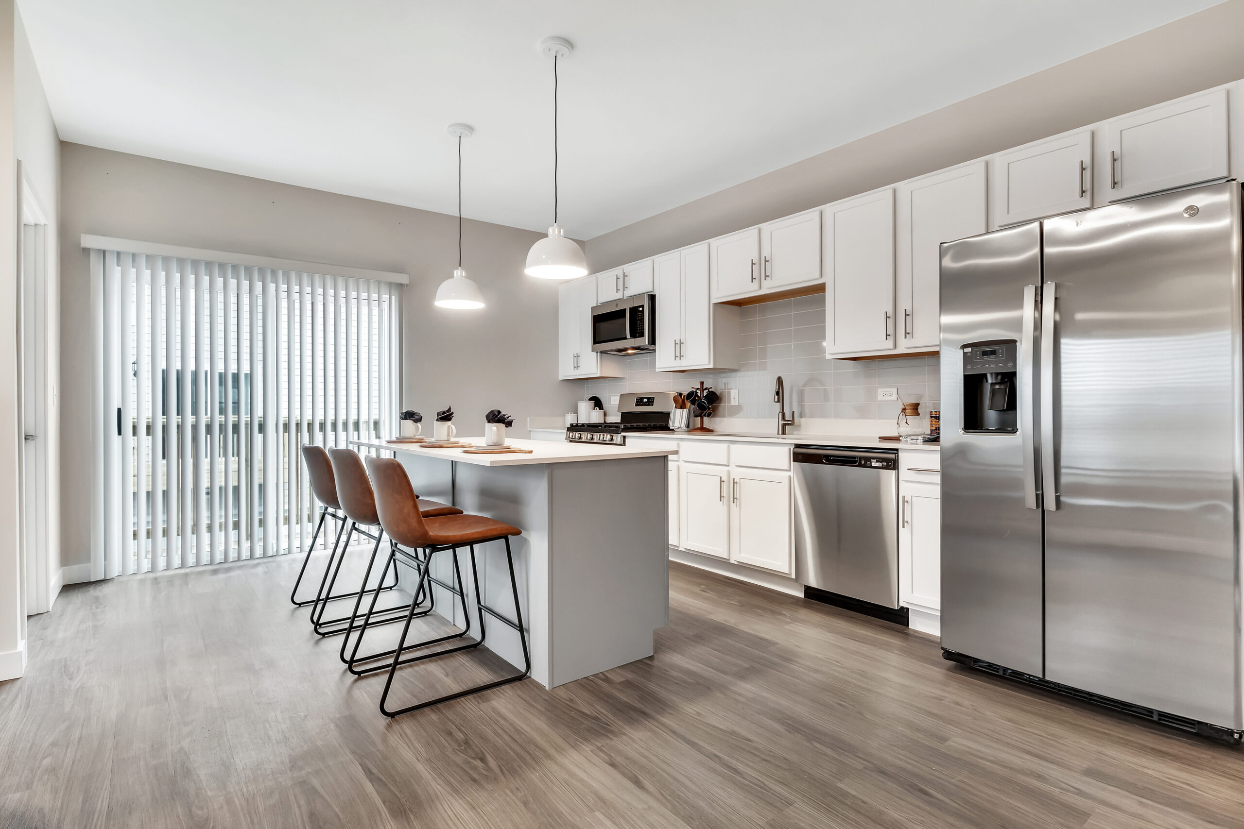 Open kitchen with an island, counter stools and stainless steel appliances at Willow Glen Apartments